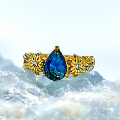 Olivenorma Ring mit blauem Topas und floralen Zirkon-Akzenten