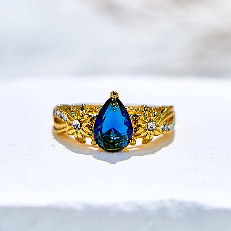 Olivenorma Ring mit blauem Topas und floralen Zirkon-Akzenten