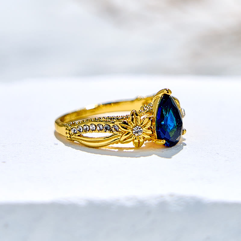 Olivenorma Ring mit blauem Topas und floralen Zirkon-Akzenten