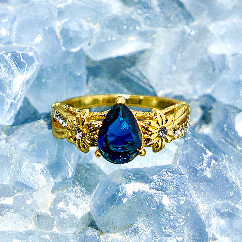 Olivenorma Ring mit blauem Topas und floralen Zirkon-Akzenten